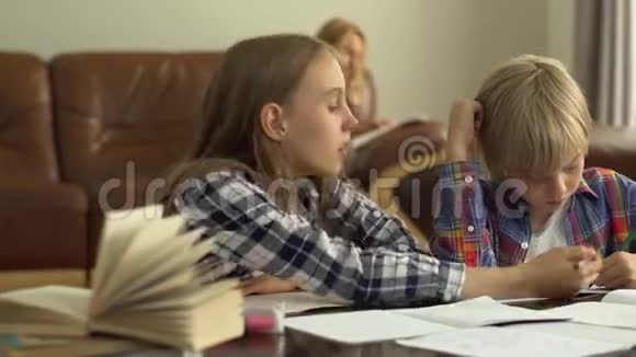 可爱的小男孩和女孩在家学习的前景而他们的母亲坐在后台小孩子们视频的预览图