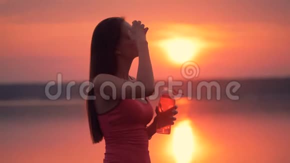 一幅美丽的风景画一个苗条的年轻女人从瓶子里喝着视频的预览图