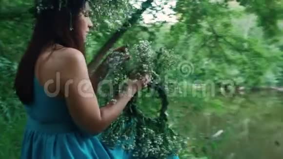美丽的女孩坐在森林里的一个湖边视频的预览图