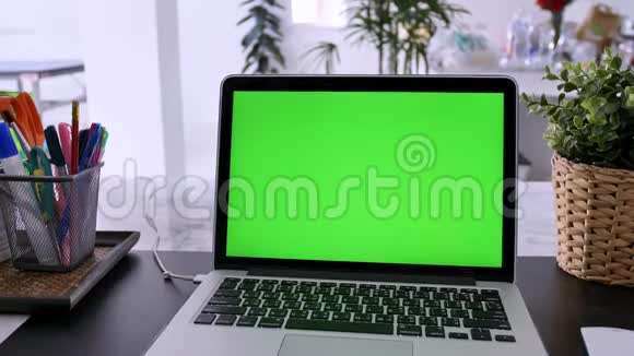 在客厅的办公桌上展示绿色彩色钥匙屏幕的笔记本电脑在背景舒适的客厅里倾斜向下视频的预览图