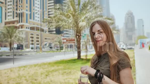 一个女孩正在迪拜市的一条街上喝一瓶水视频的预览图