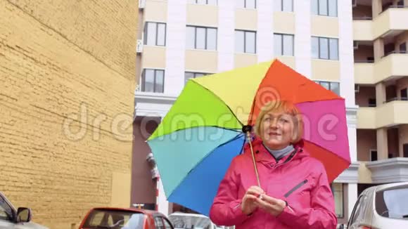在建筑背景下带着五颜六色雨伞的老妇人视频的预览图