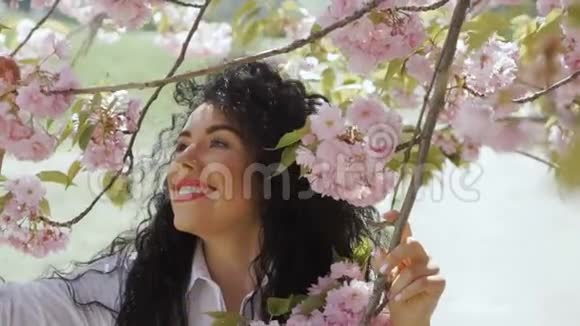 美丽微笑的黑发喜欢樱花的味道视频的预览图