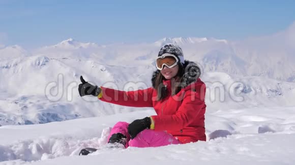 女子滑雪者在雪山的背景下展示了手的健康和手指的向上视频的预览图