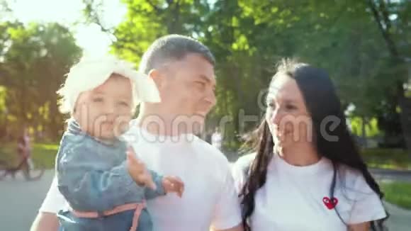 阳光明媚幸福的家庭与小女孩漫步在夏日公园视频的预览图