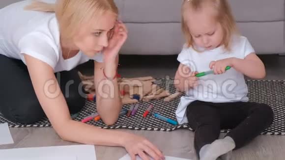 小可爱的金发女孩画毛笔她美丽的妈妈坐在沙发附近特写镜头视频的预览图