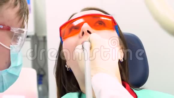 专业牙医在现代诊所与病人合作医学理念媒体戴防护眼镜的年轻病人视频的预览图