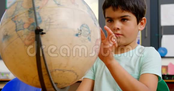 高加索学童在4k教室课桌上学习地球仪的前景视频的预览图