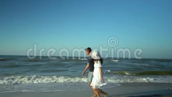 年轻漂亮的夫妇走在海边男孩和女孩他们很开心阳光灿烂慢动作他们跑了视频的预览图
