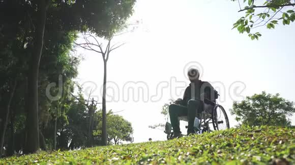 较高的亚洲人男人起立在上面从轮子椅子伸武器视频的预览图