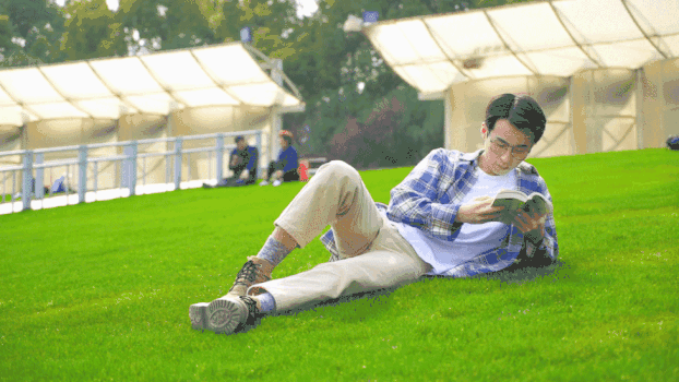 穿格子衫的男生在草地看书GIF图片素材免费下载