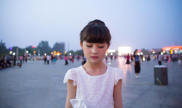 傍晚小女孩穿着白裙站在广场上闭着眼睛图片素材免费下载