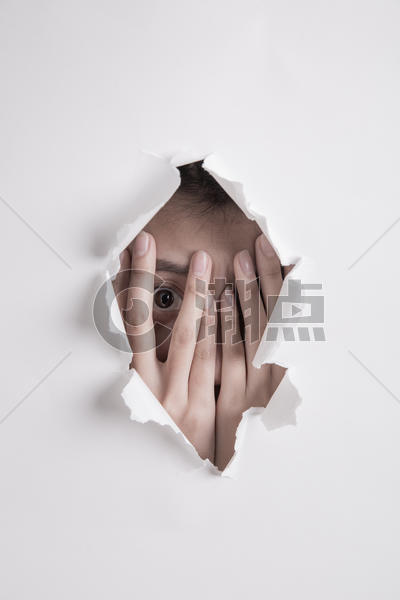 一个姑娘双手捂着眼睛躲在撕开破洞的白纸后面图片素材免费下载