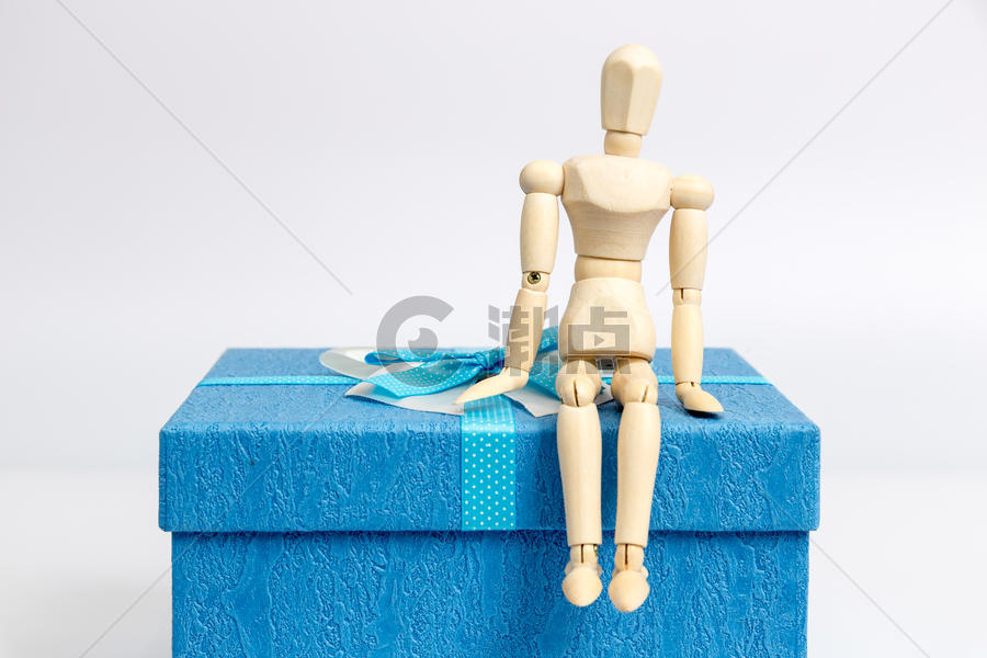 蓝色礼物盒与坐着的人偶图片素材免费下载