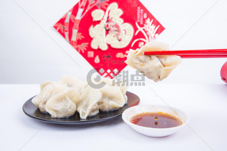 福字为背景的人夹饺子吃的冬至新春节日图片素材免费下载