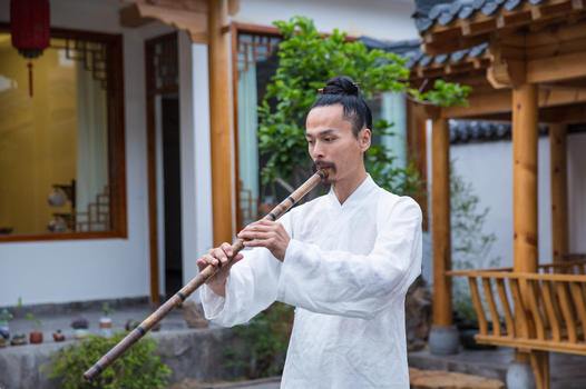 一位白衣道士在庭院内吹奏长笛图片素材免费下载