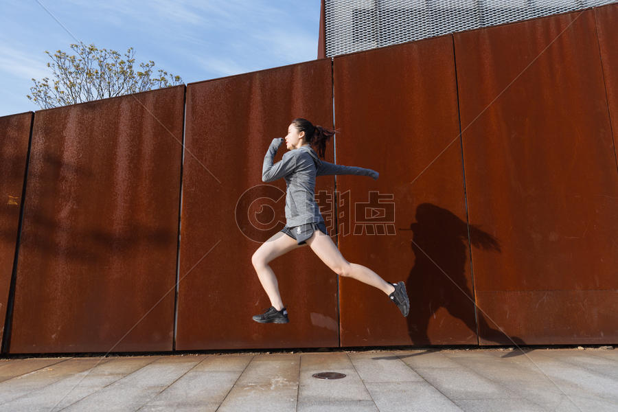 运动女孩在生锈铁板前跳跃图片素材免费下载