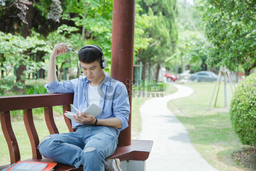 帅气大学生坐在凉亭听音乐看书图片素材免费下载