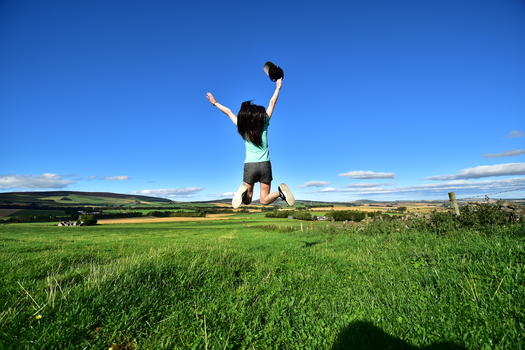 草地上跳跃的女孩图片素材免费下载