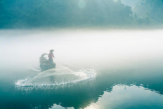 渔夫在起雾的江中撒网打鱼图片素材免费下载