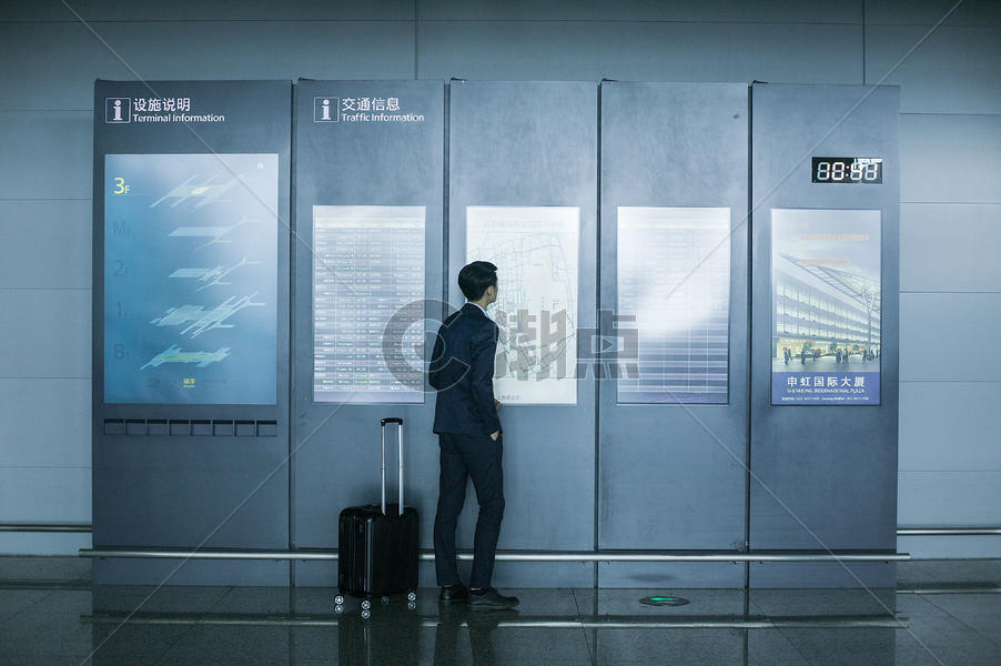 商务男士手提拉杆箱在机场时刻表上看时间图片素材免费下载