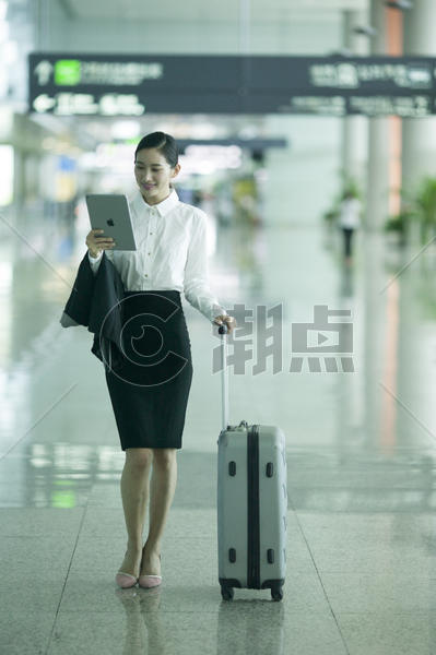 商务女士手提拉杆箱从机场大厅经过并手看ipad图片素材免费下载