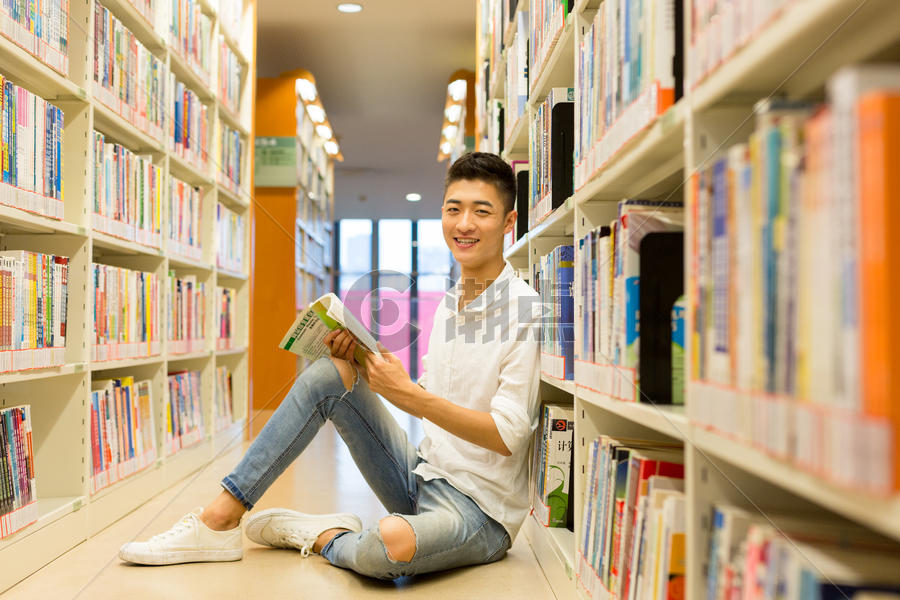 坐在图书馆书架旁看书的男生图片素材免费下载