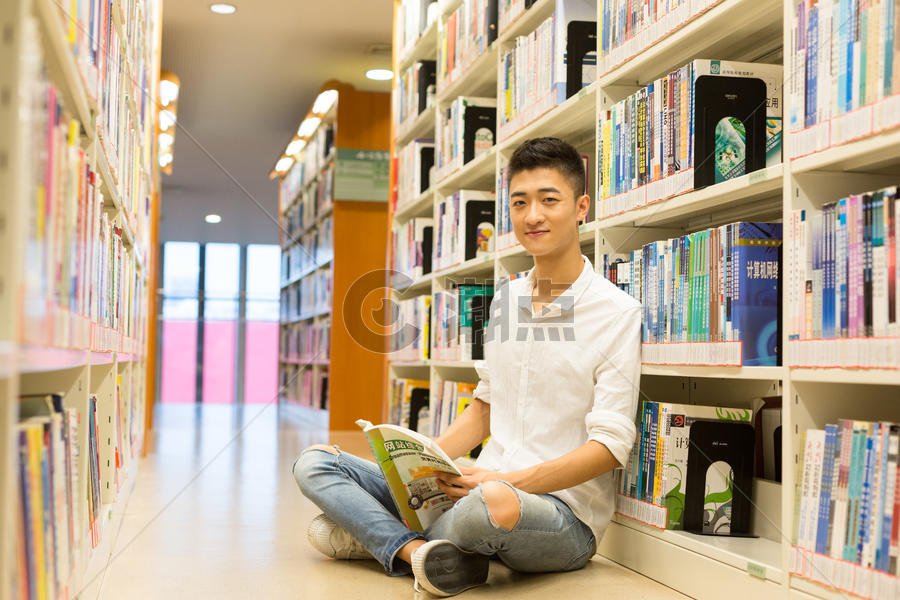 坐在图书馆书架旁看书的男生图片素材免费下载