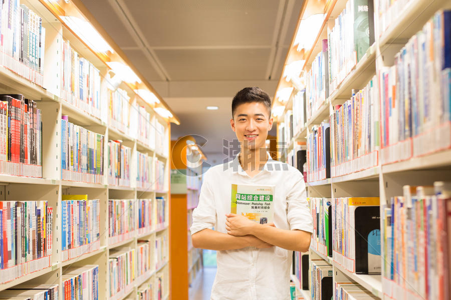 站在图书馆书架旁看书的帅气男同学图片素材免费下载