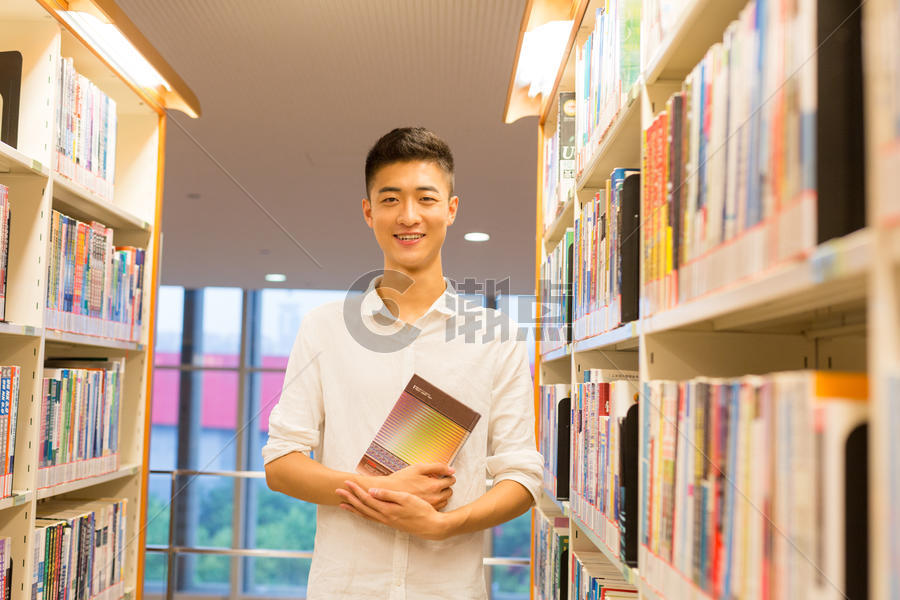 站在图书馆书架旁看书的帅气男同学图片素材免费下载
