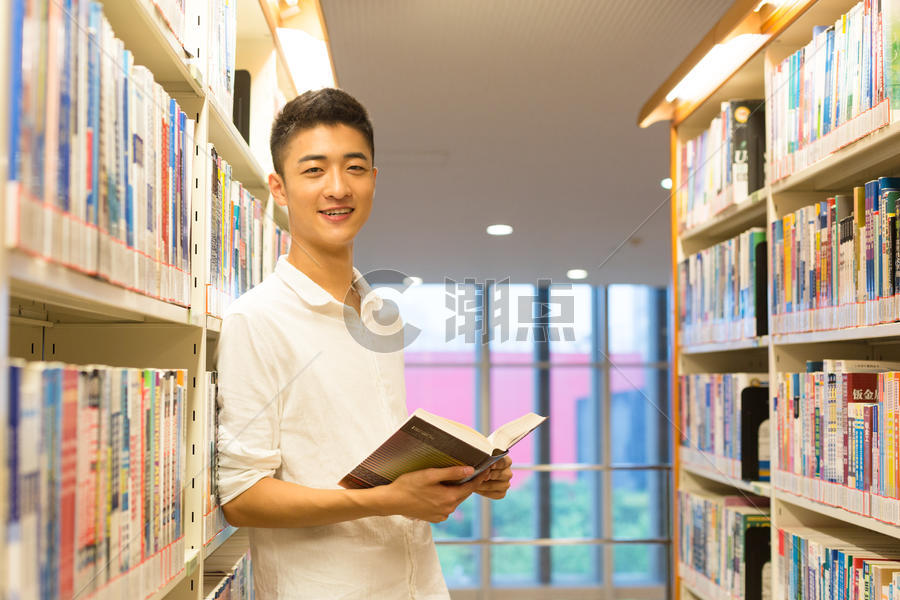 站在图书馆书架旁看书的帅气男高中生图片素材免费下载