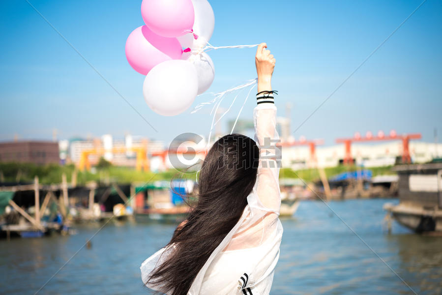 拿着气球的年轻女性背影图片素材免费下载