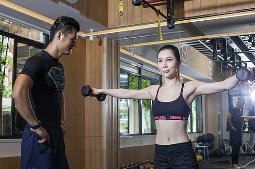 男教练在健身房给女性练习力量图片素材免费下载