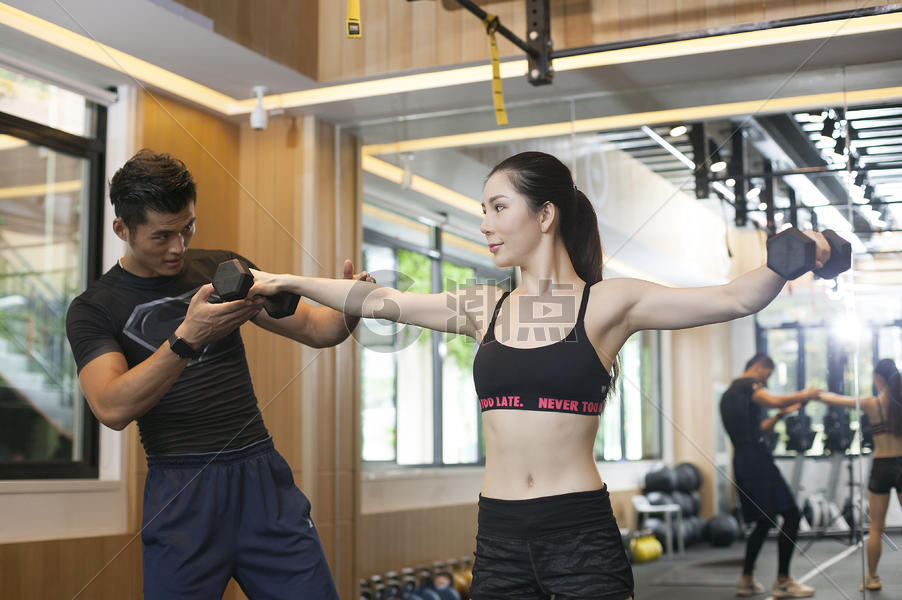 男教练在健身房给女性练习力量图片素材免费下载