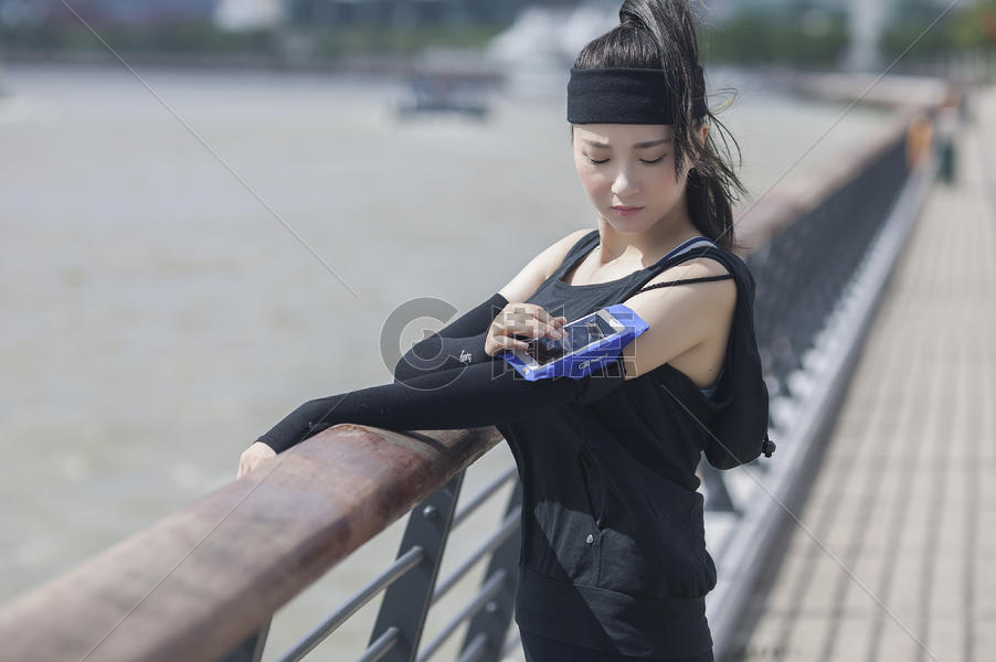 女性在户外运动时看臂弯手机图片素材免费下载