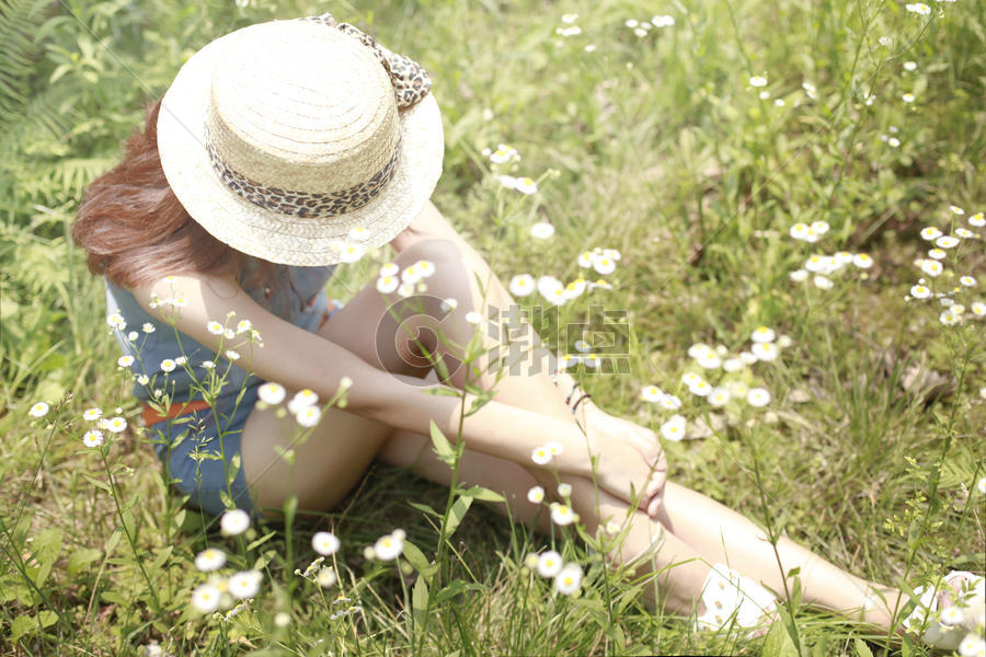 草地里坐着的戴帽子的女孩子图片素材免费下载