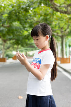 站在校园里玩手机的小学生女生图片素材免费下载