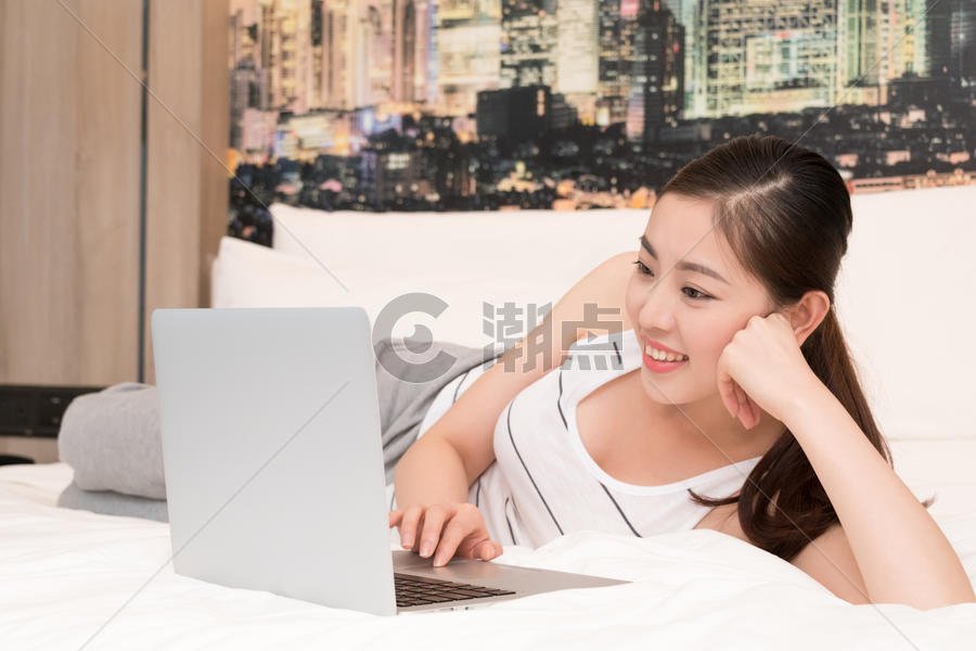 年轻女性在床上玩电脑图片素材免费下载