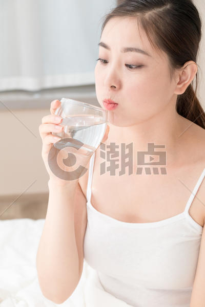 坐在床上喝水的年轻美女图片素材免费下载