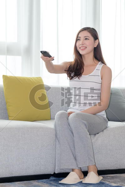 年轻女性在沙发上使用遥控器图片素材免费下载