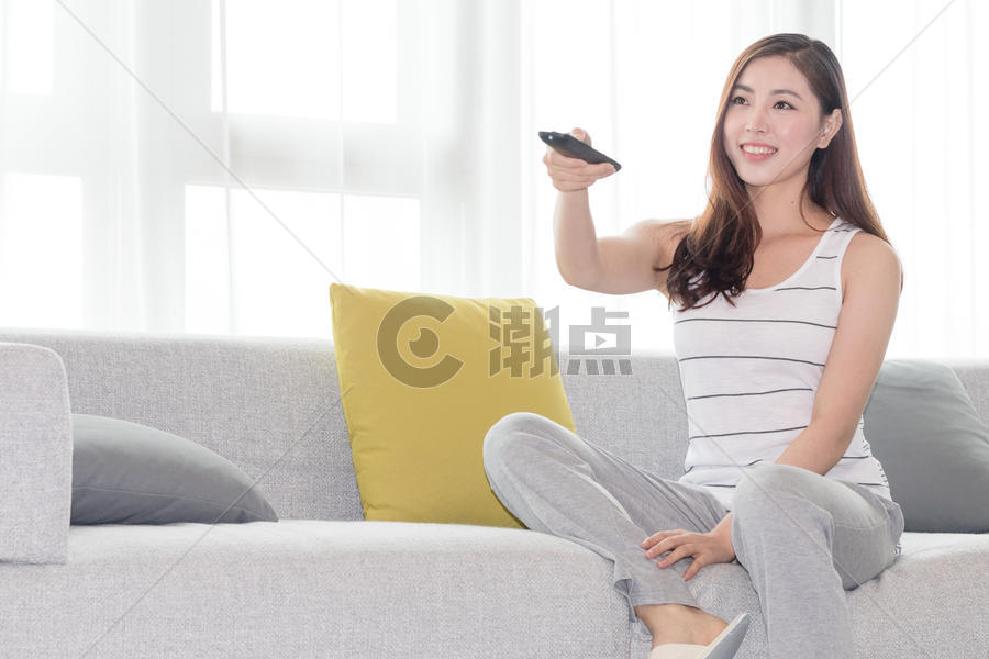 年轻女性在沙发上使用遥控器图片素材免费下载