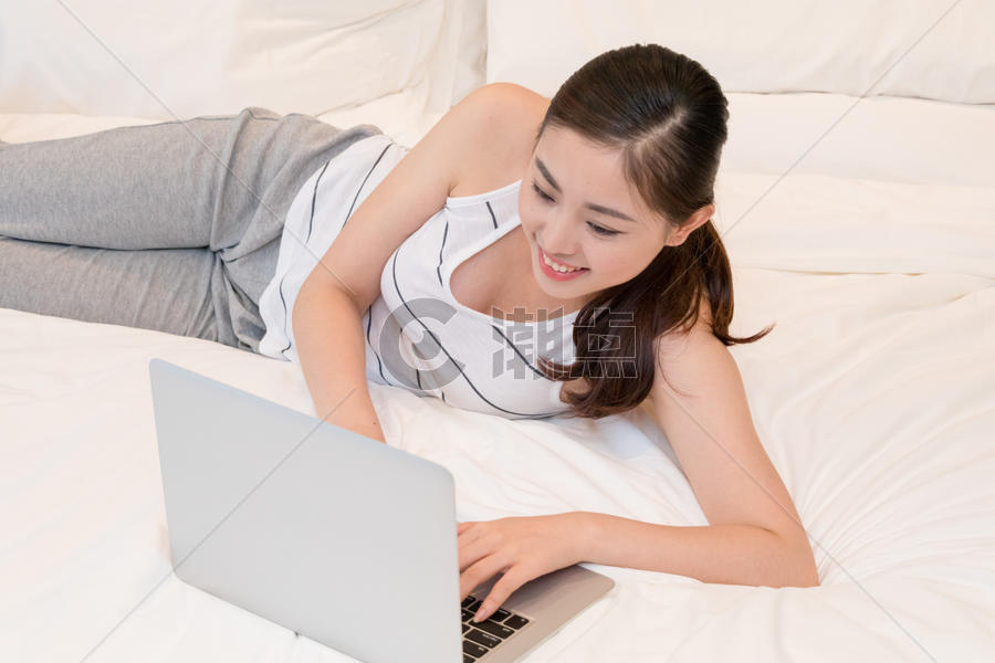 躺在床上放松地玩电脑的美女图片素材免费下载