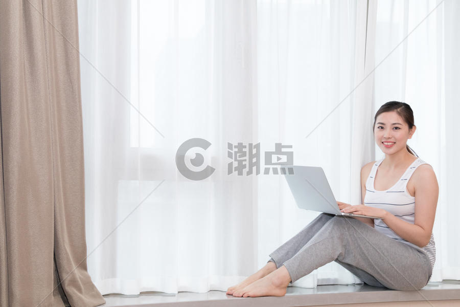 坐在客厅窗台使用笔记本电脑的美女图片素材免费下载