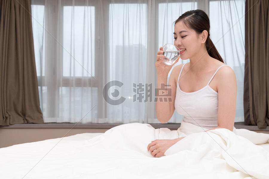 早起睡前坐在床上喝水的美女图片素材免费下载