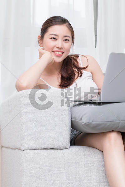 坐在沙发上使用笔记本电脑的年轻女性图片素材免费下载