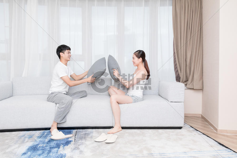 年轻情侣夫妻在客厅抢枕头图片素材免费下载