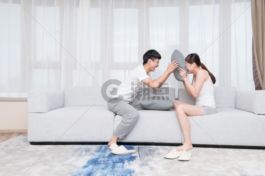年轻情侣夫妻在客厅抢枕头图片素材免费下载