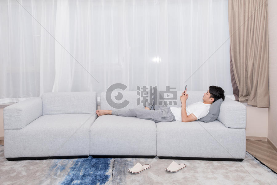 男生躺在沙发上玩手机购物图片素材免费下载