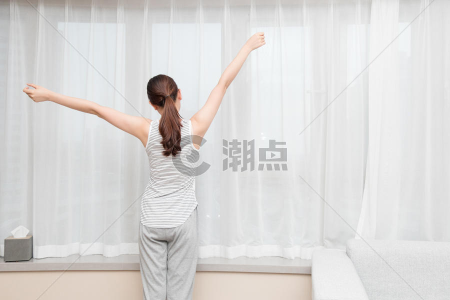 年轻女性在客厅窗前伸展运动图片素材免费下载