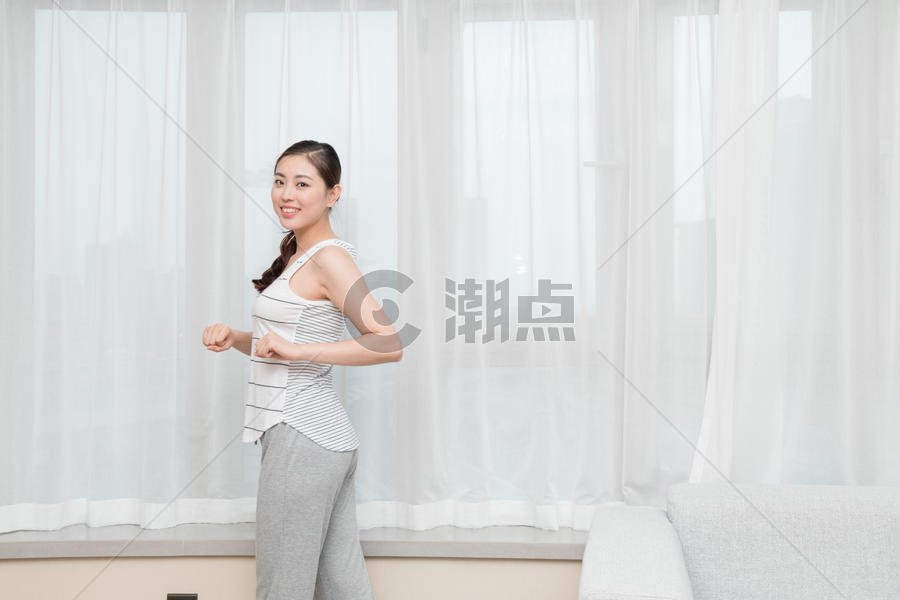 年轻女性在客厅窗前伸展运动图片素材免费下载
